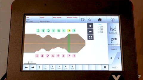 Close-up of a digital key-cutting machine displaying a numerical key code on its screen.