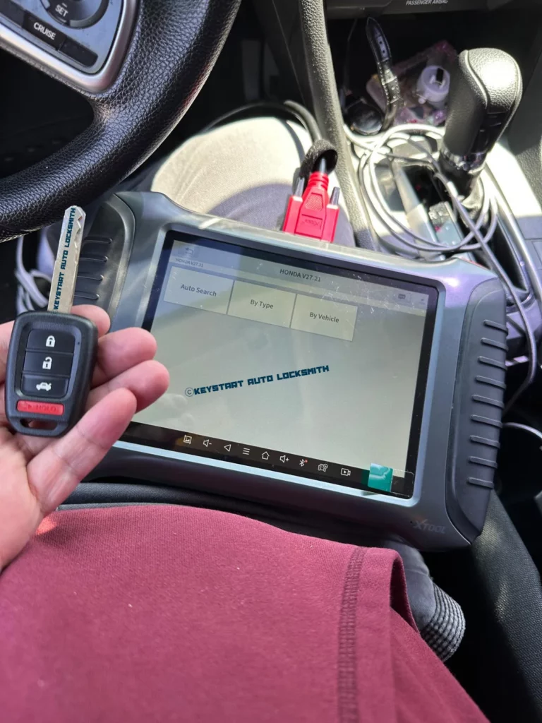 Technician using diagnostic equipment beside a dashboard while pairing a new key fob.